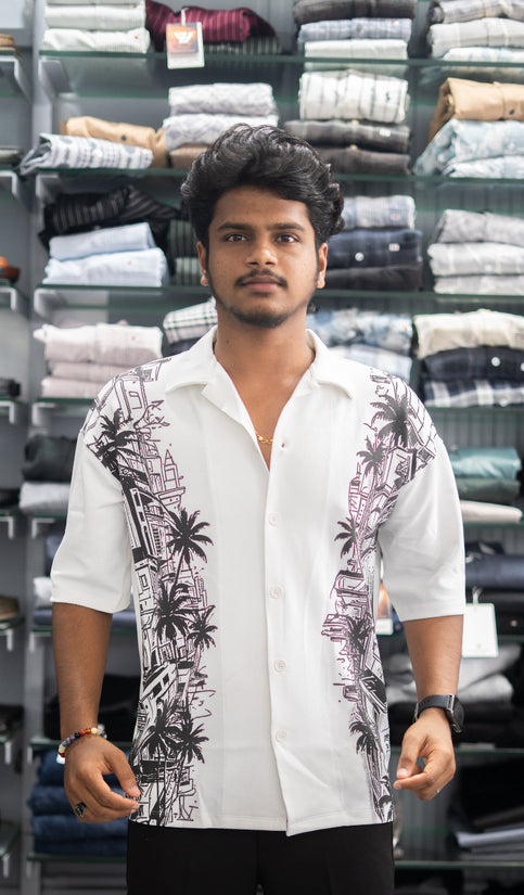Man wearing a white shirt with black patterns in a clothing store.
