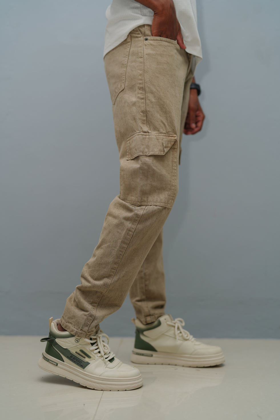 Person wearing beige cargo pants and white sneakers with green accents against a plain background